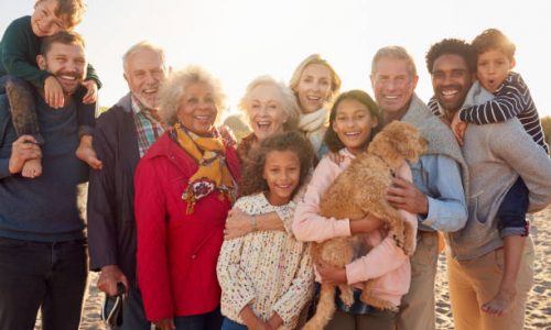 Portrait Of Multi-Generation Family Group With Dog On Winter Beach Vacation