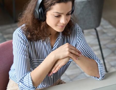 Hispanic girl college student wearing headphones watching distance online learning web class, remote university webinar or having talk on laptop video call virtual meeting seminar at home or campus.