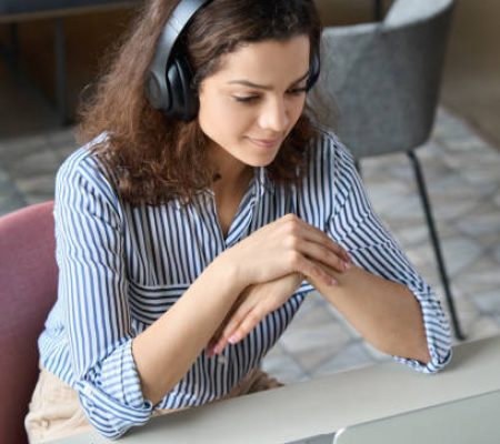 Hispanic girl college student wearing headphones watching distance online learning web class, remote university webinar or having talk on laptop video call virtual meeting seminar at home or campus.